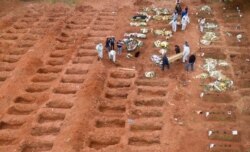Cemetery workers in protective clothing bury three victims of the new coronavirus at the Vila Formosa cemetery in Sao Paulo, Brazil, July 15, 2020.