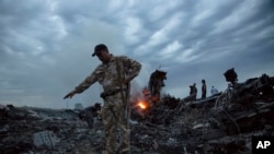 FILE - People walk amongst the debris at the crash site of a Malaysia Airlines flight MH17 near the village of Grabove, Ukraine, July 17, 2014.