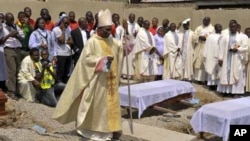 Clergymen gather around victims' coffins for mass burial after Christmas day bombing at St. Theresa Catholic Church, Madalla, Nigeria, Feb. 1, 2012.