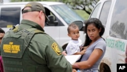 A mother migrating from Honduras holds her 1-year-old child as surrendering to U.S. Border Patrol agents after illegally crossing the border Monday, June 25, 2018, near McAllen, Texas. (AP Photo/David J. Phillip)