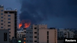 Asap dan api tampak terlihat di atas sebuah gedung di tengah konflik antara pasukan Israel dan Palestina di Gaza, pada 20 Mei 2021. (Foto: Reuters/Mohammed Salem)