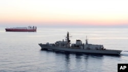 FILE - The British navy vessel HMS Montrose escorts a ship at sea off the coast of Cyprus, February 2014. The British navy said it intercepted an attempt, July 11, 2019, by three Iranian vessels to impede passage of a British commercial vessel.