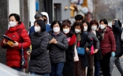 People wearing masks stand in a line to buy face masks in front of a drug store amid the rise in confirmed cases of COVID-19 in Daegu, South Korea, March 3, 2020.