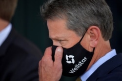 Georgia Gov. Brian Kemp adjusts his mask prior to a bill signing at Wellstar Kennestone Hospital where the hospital opened a new emergency room space, July 16, 2020, in Marietta, Ga.