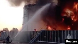 Members of the Russian emergencies ministry work to extinguish fire at an oil storage tank after an alleged drone attack in the town of Azov in Rostov, Russia, June 18, 2024, in this still image ttaken from video. Russian Emergencies Ministry/Handout via REUTERS.