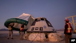 Boeing, NASA, and U.S. Army personnel work around the Boeing Starliner spacecraft shortly after it landed in White Sands, N.M., Dec. 22, 2019. 