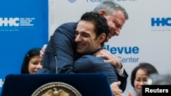 Walikota New York Mayor Bill de Blasio (kiri) memeluk bekas pasien ebola, dokter Craig Spencer setelah dinyatakan sembuh dan diperbolehkan meninggalkan rumah sakit Bellevue di New York, Selasa (11/11).
