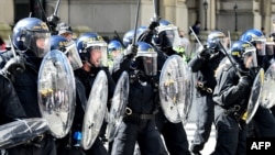 Police officers in riot gear gesture with batons during a demonstration held in reaction to the fatal stabbings in Southport on July 29, outside the Liver Building in Liverpool, England, on Aug. 3, 2024.