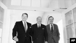 Sur cette photo datant du 9 janvier 1985, le secrétaire d'État George Shultz, au centre, marche avec le président Ronald Reagan et le vice-président George Bush à la Maison Blanche à Washington. 