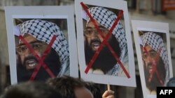 FILE - Indian activists carry placards of the leader of the Pakistan-based Jaish-e-Mohammad group, Masood Azhar, during a protest denouncing an attack on the Indian air force base in Pathankot, in Mumbai, India, Jan. 4, 2016.