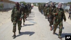 FILE - Members of Somalia's al-Shabab militant group patrol on foot on the outskirts of Mogadishu, March 5, 2012. Somalia now says al-Shabab militants are plotting to supply uranium to Iran.