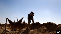 A Kurdish Peshmerga fighter uses binoculars to check on Islamic State group's positions on the outskirts of Makhmour, 300 kilometers (186 miles) north of Baghdad, Iraq, Sept. 6, 2014. 