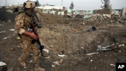 FILE - An Afghan security forces member walks next to a crater caused by suicide bomb attack in Kabul, Afghanistan, Nov. 29, 2018.