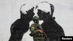 Un miembro de las fuerzas del orden hace guardia frente a un mural en las calles de Quito, el 14 de agosto de 2023.