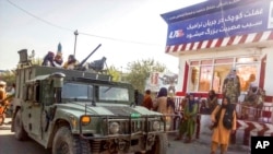 FILE - Taliban fighters stand guard at a checkpoint in Kunduz city, northern Afghanistan, Aug. 9, 2021. As the Taliban took control of Afghanistan in a swift power grab, thousands of Afghans have been looking for ways to escape.