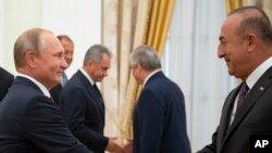 Russian President Vladimir Putin, left, shakes hands with Turkish Foreign Minister Mevlut Cavusoglu during their meeting in the Kremlin in Moscow, Russia, Aug. 24, 2018. 