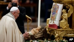 Le pape François touche une statue de l'Enfant Jésus lors de la célébration de la messe du réveillon du Nouvel An dans la basilique Saint-Pierre au Vatican, 31 décembre 2015. 