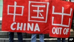 Filipino environmental activists hold slogans during a rally outside the Chinese Consulate in suburban Makati, south of Manila, Philippines, May 11, 2015 