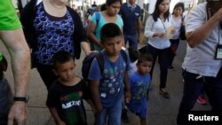 Migrant families from Mexico, fleeing from violence, walk toward the United States to meet officers of the U.S. Customs and Border Protection to apply for asylum at Paso del Norte international border crossing bridge in Ciudad Juarez, June 20, 2018. 