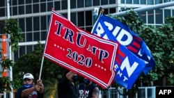 FILE - Supporters of U.S. President Donald Trump and Democratic presidential nominee and former Vice President Joe Biden wave flags of the Perez Art Museum in Miami, Florida, Oct. 5, 2020. 