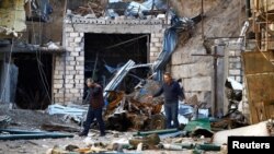 Men walk through the ruins after recent shelling during the military conflict over the breakaway region of Nagorno-Karabakh, Oct. 13, 2020. 