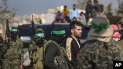 အကျဥ်းသားလဲလှယ်ရေးအစီအစဥ်အရ လွတ်မြောက်လာသည့် အစ္စရေးလ်နွယ်ဖွား အမေရိကန်နိုင်ငံသား Sagui Dekel Chen ကို ကြက်ခြေနီအဖွဲ့ထံသို့ လွှဲပြောင်းပေးရန် ခေါ်ဆောင်လာသည့် ဟားမတ်စ်အဖွဲ့ဝင်များ။ (၁၅ ဖေဖော်ဝါရီ ၂၀၂၅)​ (AP)