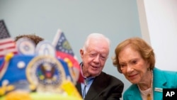 FILE - In this Saturday, Oct. 4, 2014, file photo, former President Jimmy Carter, left, and former first lady Rosalynn Carter look at a birthday cake during Jimmy Carter's 90th birthday celebration held at Georgia Southwestern University, in Americus, Ga.