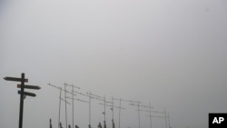 Pilgrims walk past sculptures indicating the direction of St. James' Way in El Perdon mountain, near to Pamplona northern northern Spain, June 1, 2021.