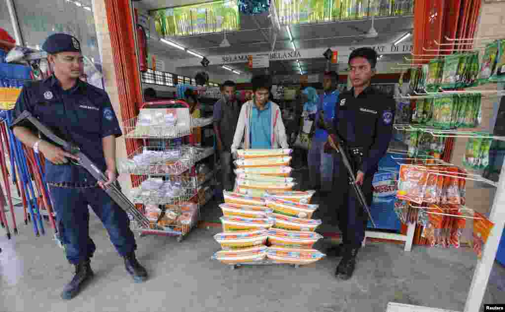 Malaysian police monitor the delivery of goods to a grocery store in Felda Sahabat near where Malaysian troops stormed the camp of an armed Philippine group, March 6, 2013. 