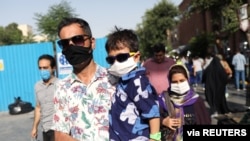 People wearing protective face masks walk in a street, following the outbreak of the coronavirus disease (COVID-19), in Tehran, Iran, June 28, 2020.