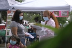 FILE - A 'promotora' (health promoter) from CASA, a Hispanic advocacy group, tries to enroll Latinos as volunteers to test a potential COVID-19 vaccine, at a farmers market in Takoma Park, Md., on Sept. 9, 2020.