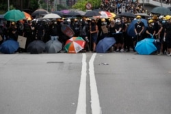 Protesters face off against riot police at the entrance to a village at Yuen Long district in Hong Kong, July 27, 2019. Protesters wearing black streamed through Yuen Long, even though police refused to grant permission for the march.