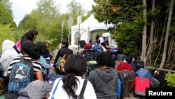 FILE - A line of asylum seekers who identified themselves as from Haiti wait to enter into Canada from Roxham Road in Champlain, New York, Aug. 7, 2017.