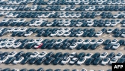 တရုတ်နိုင်ငံတွင်း သယ်ယူဖို့စောင့်နေတဲ့ လျှပ်စစ်ကား (EV) နဲ့ စွမ်းအင်နှစ်မျိုးသုံး (hybrid) ကားတွေကို တွေ့ရစဉ် (ဇန်နဝါရီ ၁၂၊ ၂၀၂၅)