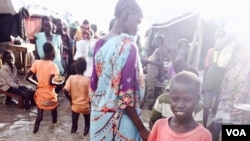 A child stands in floodwaters at a camp for people displaced by violence, Bentiu, South Sudan (G. Joselow/VOA).