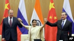 Indian Foreign Minister Sushma Swaraj, center, holds hands with her Chinese and Russian counterparts Wang Yi, right and Sergey Lavrov after a press statement at the end of their meeting in New Delhi, India, Monday, Dec. 11, 2017. 