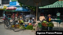 FILE - Street vendors sell vegetables on a street in Shwebo township in Sagaing region, Myanmar, Oct. 10, 2021.