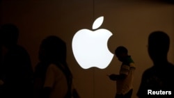 FILE PHOTO: A man looks at the screen of his mobile phone in front of an Apple logo outside its store in Shanghai