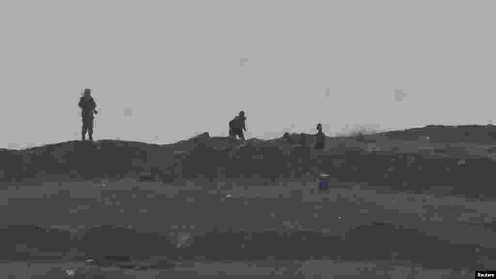 Armed men, presumed by local sources to be Islamic State fighters, are pictured at a checkpoint in the west of Syrian town of Kobani, seen from near the Mursitpinar border crossing on the Turkish-Syrian border in the southeastern town of Suruc in Sanliurfa province, Oct. 13, 2014. 