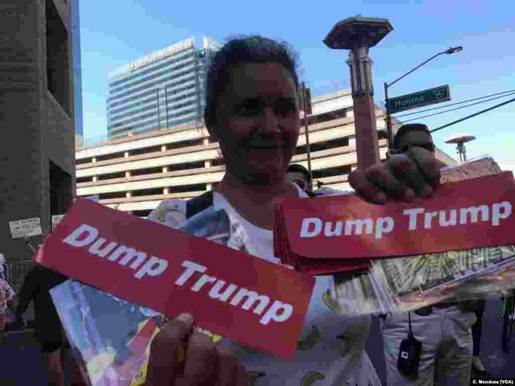 A woman holds signs protesting President Donald Trump outside his campaign-style rally in Phoenix, Aug. 22, 2017.