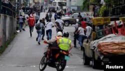 La gente huía de la policía durante los disturbios en reclamo de alimentos en Caracas, Venezuela, el jueves, 2 de junio de 2016.