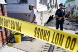 A police officer stands guard as a man surveys the damage to a home where people died after their basement apartment flooded, in the Jamaica neighborhood of the Queens borough of New York City, Sept. 2, 2021.