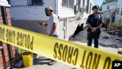 A police officer stands guard as a man surveys the damage to a home where people died after their basement apartment flooded, in the Jamaica neighborhood of the Queens borough of New York City, Sept. 2, 2021.