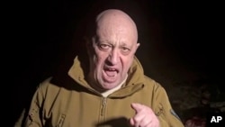 Kepala Grup Wagner Yevgeny Prigozhin berdiri di depan banyak mayat yang tergeletak di tanah di lokasi yang tidak diketahui. (Foto: via AP)