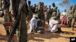 Foto yang dirilis oleh tim pendukung pasukan gabungan Uni Afrika dan PBB ini memperlihatkan tersangka anggota al-Shabab yang ditutup matanya dan dikawal ketat di sebuah kantor polisi oleh tentara Somalia (SNA) di Kismayo, selatan Somalia (3/10). Pasukan asing dilaporkan melancarkan serangan fajar di rumah persembunyian tokoh al-Shabab di kota Brava, Sabtu (5/10).