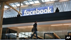 FILE - Facebook's logo is displayed in a startup companies gathering at Paris' Station F, in Paris, Jan. 17, 2017.