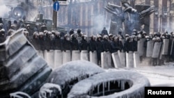 Polisi berjaga-jaga di tempat bentrokan dengan para demonstran anti-pemerintah di Kyiv (24/1).