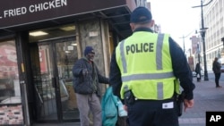A police officer asks a man to keep moving in an effort to encourage social distancing at an intersection in Newark, N.J., March 26, 2020. 