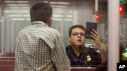 FILE - A Customs and Border Protection officer checks the passport of a non-resident visitor to the United States inside immigration control at McCarran International Airport, Dec. 13, 2011, in Las Vegas, Nevada. A new U.S. government report has found that most extremists linked to terror-related activity in the U.S. became radicalized years after entering the country.