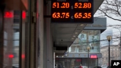 People walk past a display with currency exchange rates in central of Moscow, Russia, Dec. 1, 2014. 